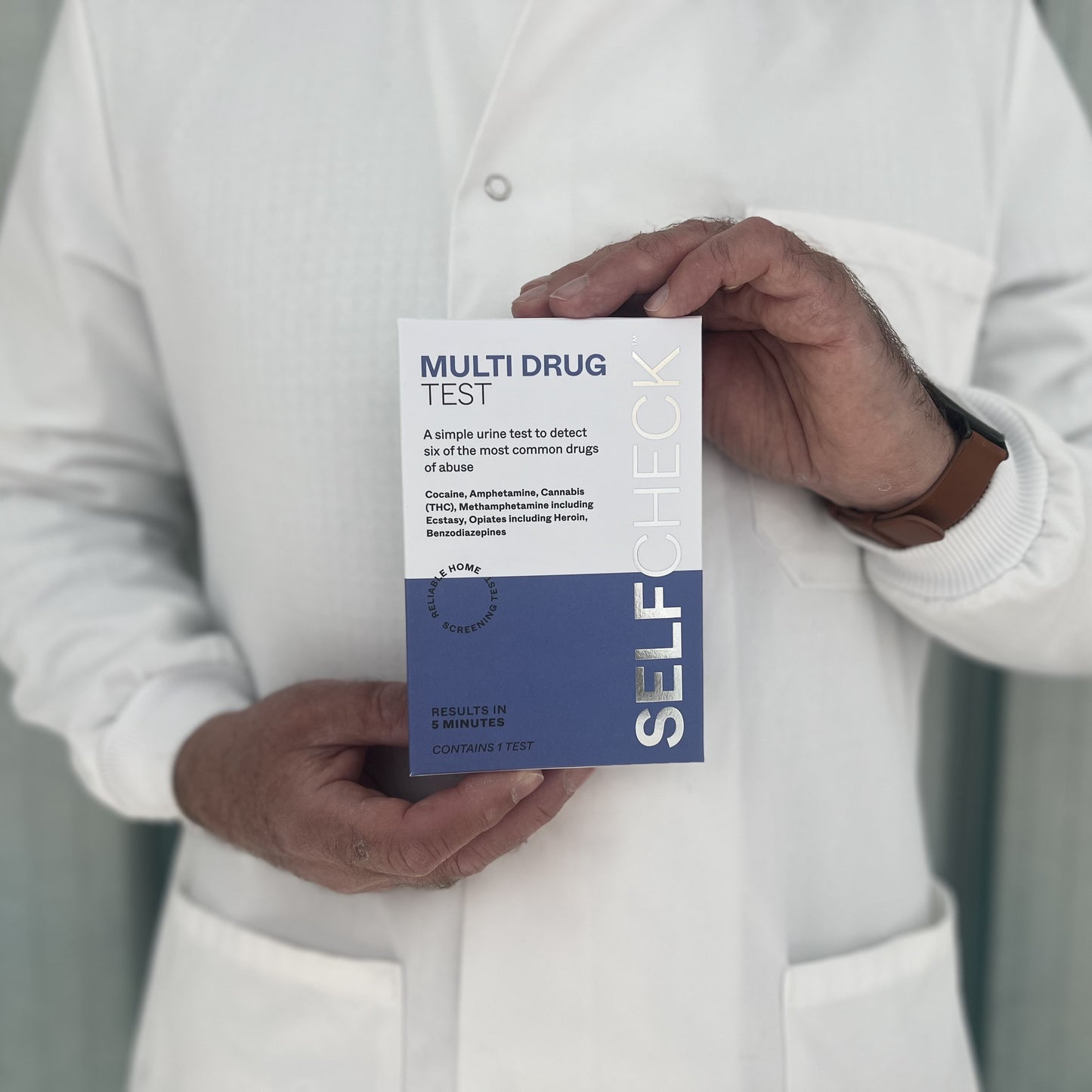 Scientist in white lab coat holding a SELFCHECK Test Kit for drug testing