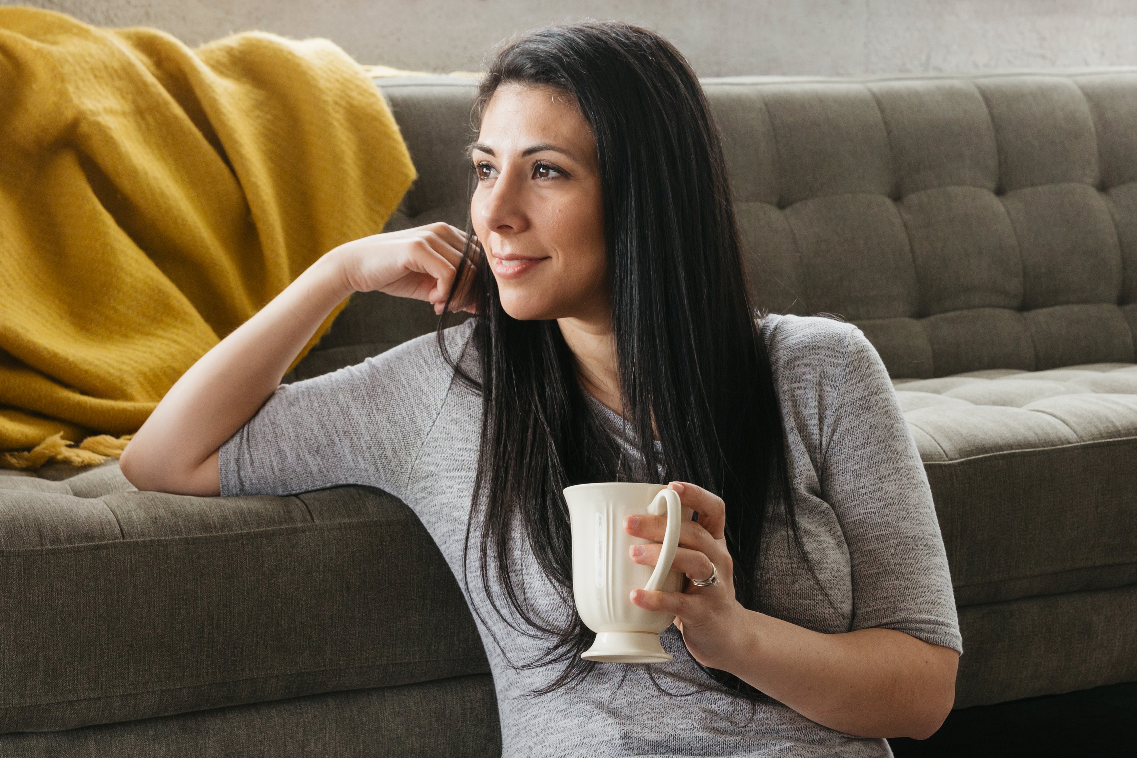 A woman sat with a coffee next to a sofa